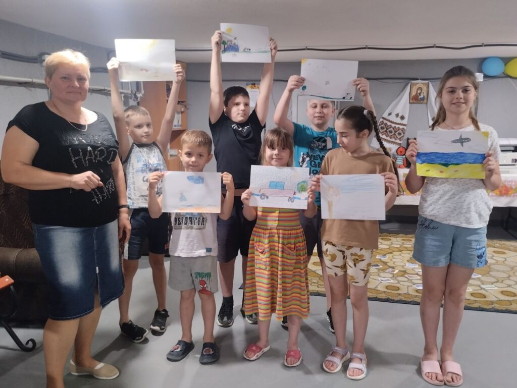 Учасники заходу разом з бібліотекаркою; діти демонструють свої малюнки