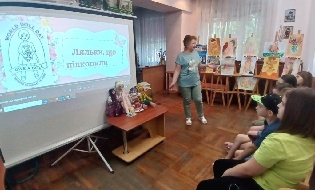 Діти слухають розповідь бібліотекаря, розглядаючи ляльок на інсталяції та переглядаючи презентацію
