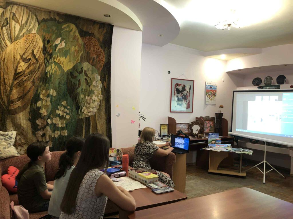 Учасники заходу переглядають презентацію на великому екрані, спілкуючись із бібліотекаркою