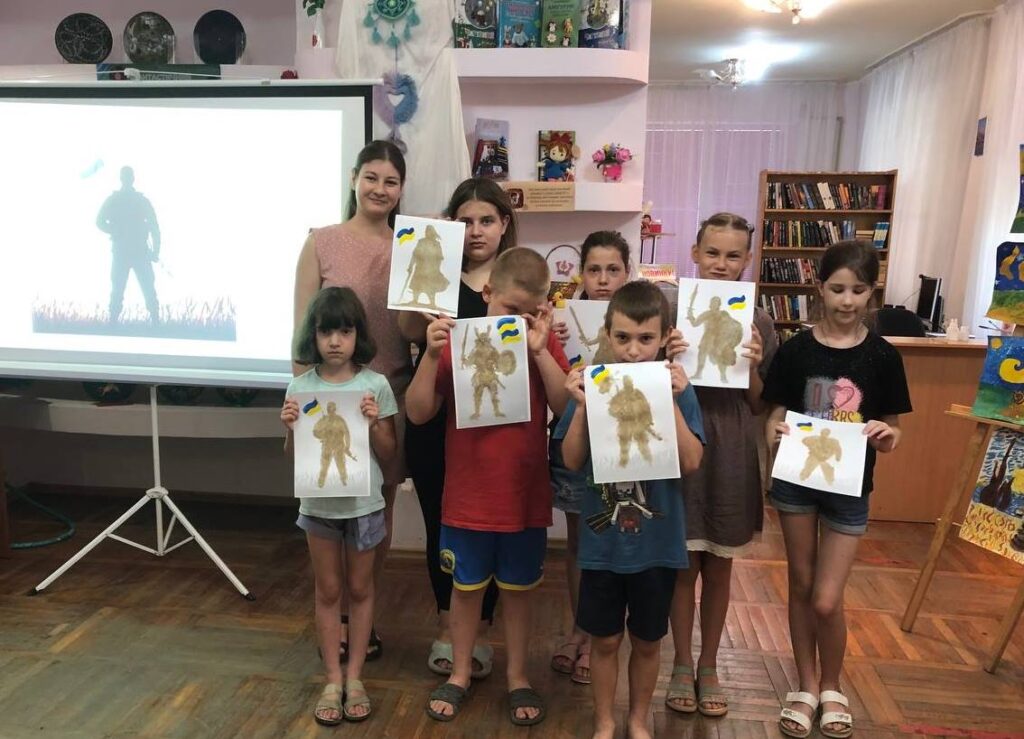 Учасники майстерки демонструють свої піщані малюнки - зображення українських воїнів