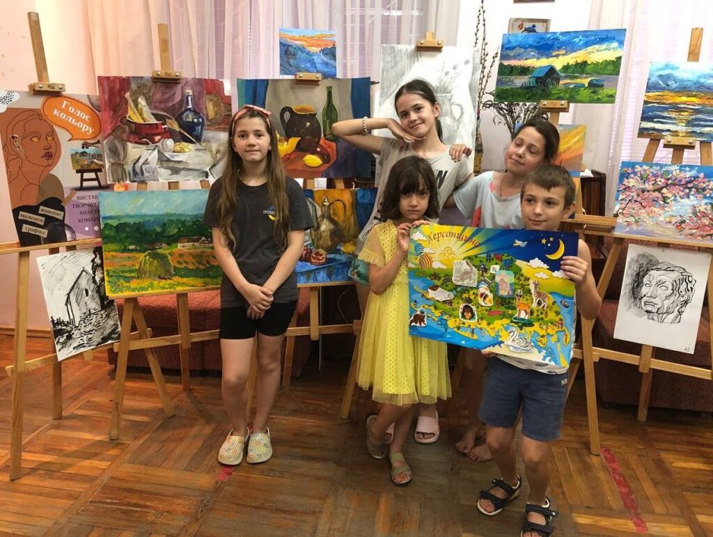 Діти на фоні малюнків із колажем - мапою тваринного світу Херсонщини
