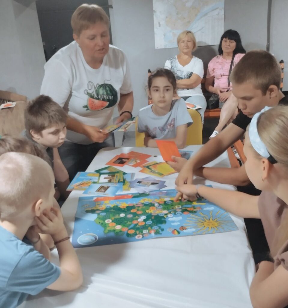 Діти грають з бібліотекаркою у настільну гру "Мистецька палітра Херсонщини"