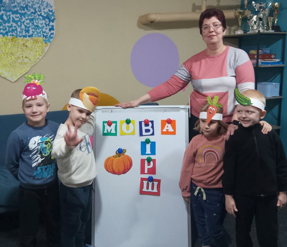 Маленькі учасники програми разом з бібліотекаркою біля фліпчарта з викладеними з літер словами "мова" і "вірш"