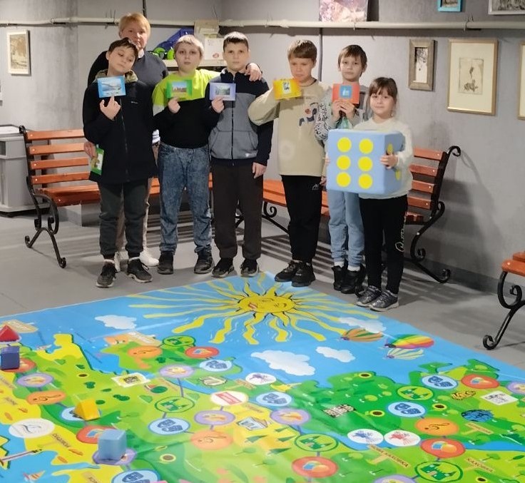 Учасники гри, проведеної в укритті, перед якими розгорнуте велике ігрове поле-"килим"