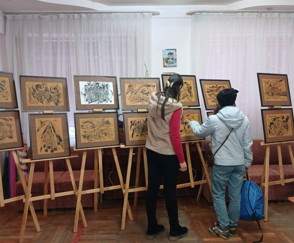 Двоє відвідувачів розглядають експозицію виставки