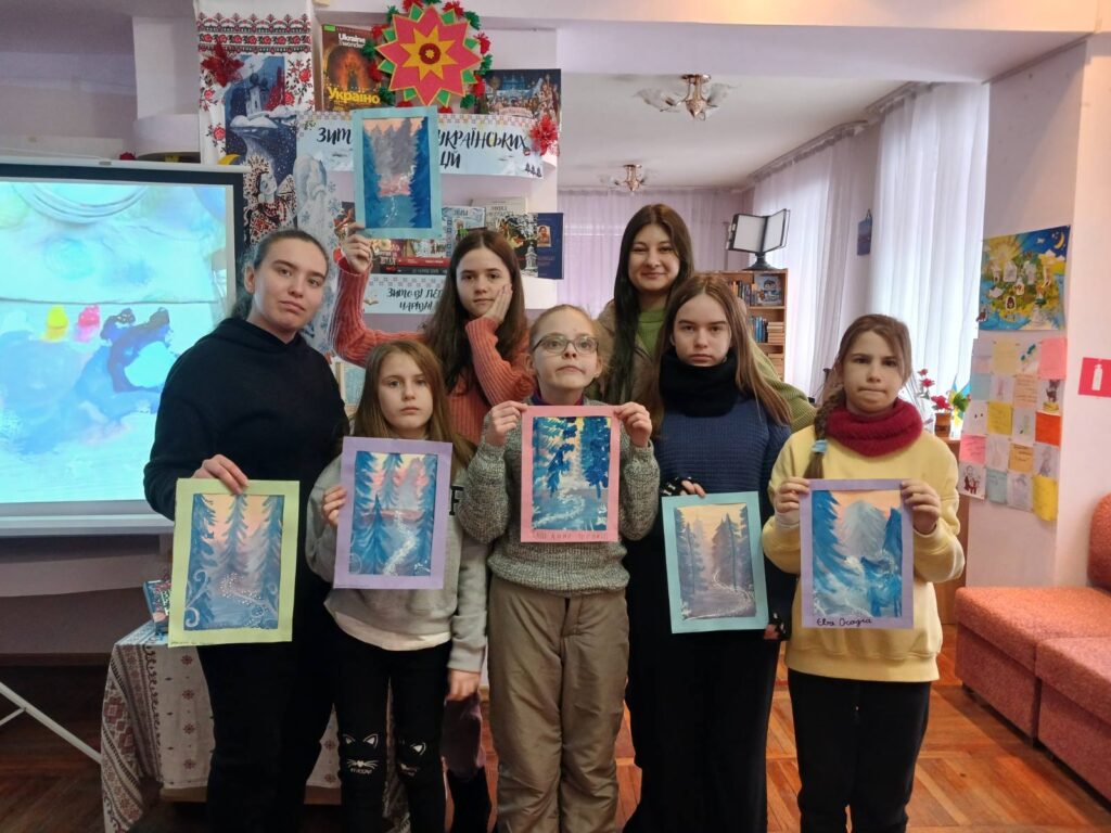 Учасниці художньої студії демонструють свої малюнки засніжених зимоих ялин