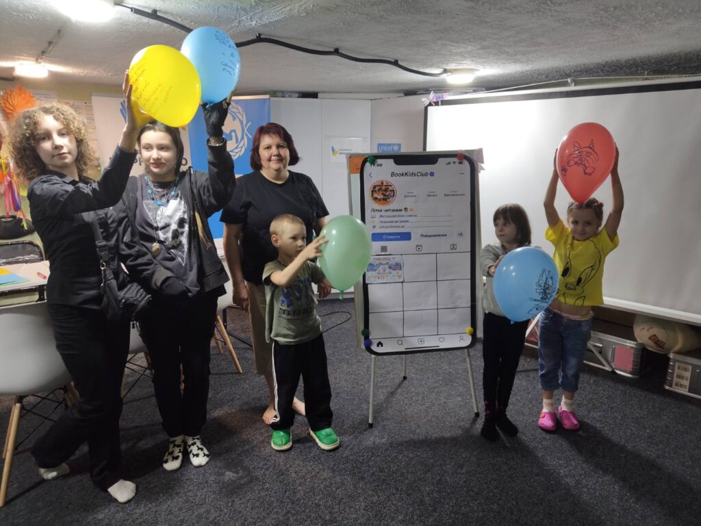 Учасники "мистецького пікніка" біля сторінки "паперового Instagram" на фліпчарті