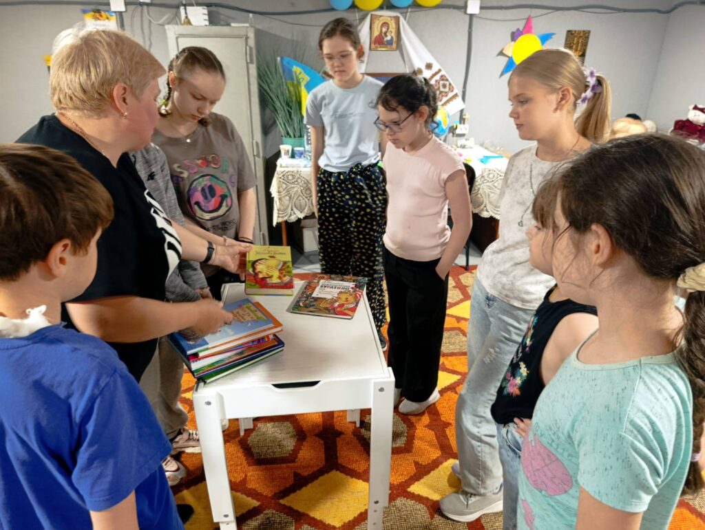Учасники BookKidsClub на ароматичних читаннях переглядають добірку книг, підготовлену для них бібліотекаркою
