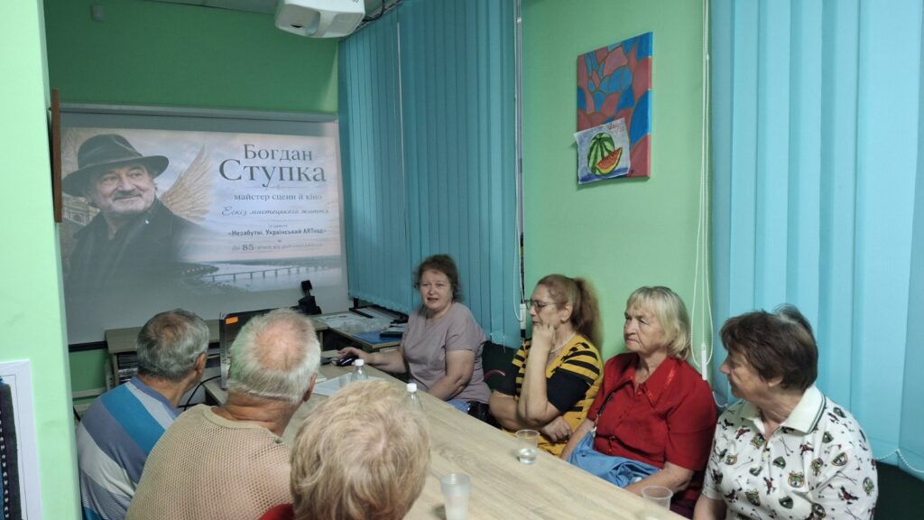 Учасники зустрічі переглядають презентацію, слухаючи розповідь бібліотекарки