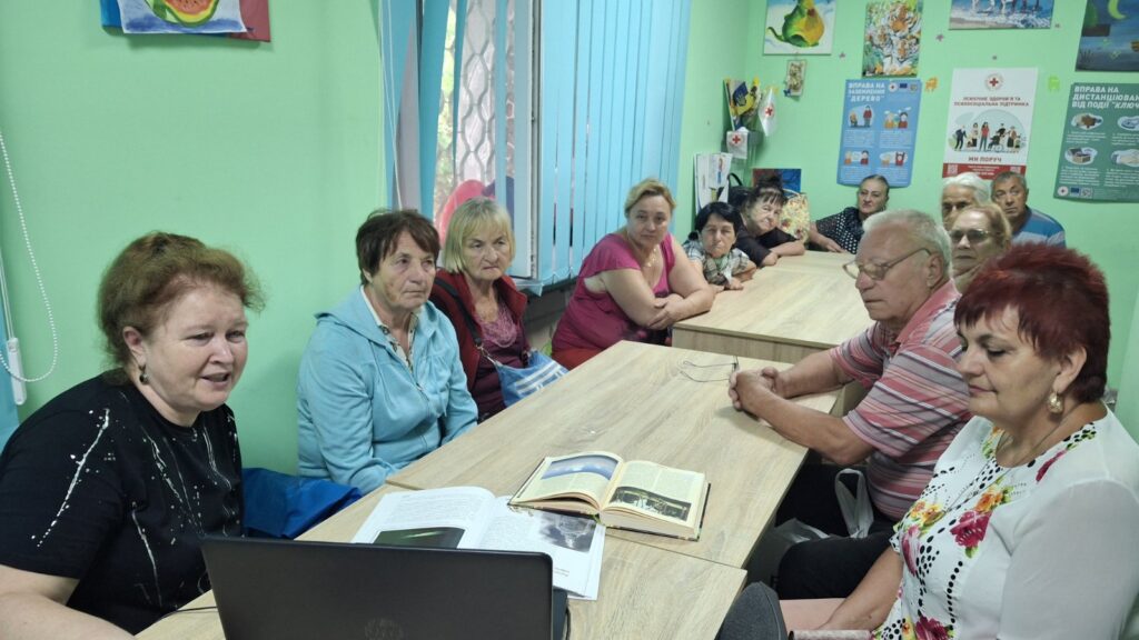 Учасники мистецької зустрічі слухають розповідь бібліотекарки, що супроводжується мультимедійною презентацією