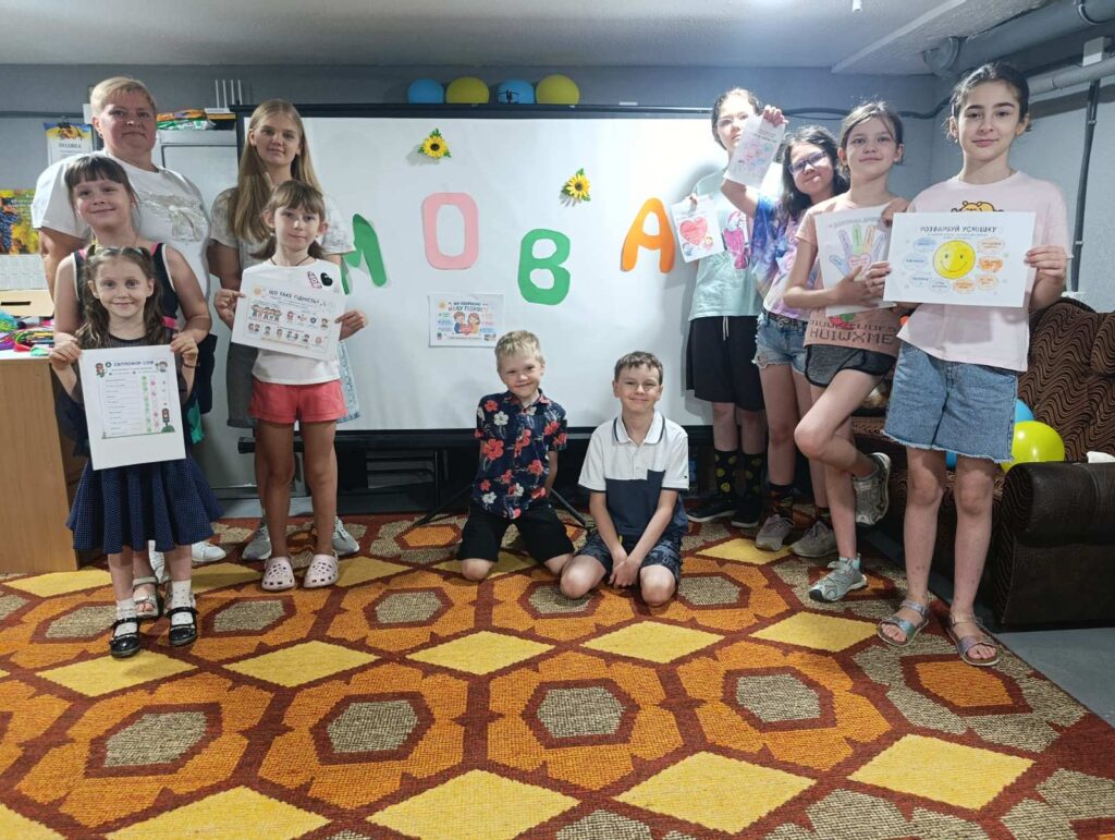 Учасники заходу біля екрану, прикрашеного написом "Мова"